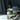 Glass dropper bottle of ritual oil with dried botanicals on a marble surface with light refracting